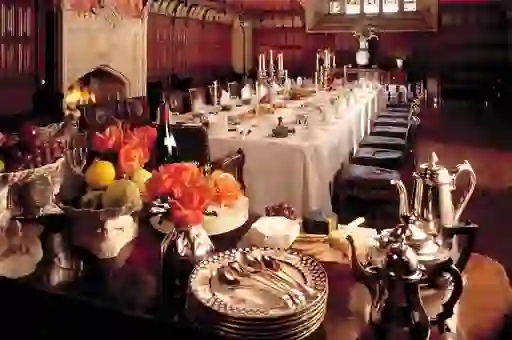 Long candlelit dining table set for a formal banquet in a wood-panelled room at Lismore Castle, Waterford.