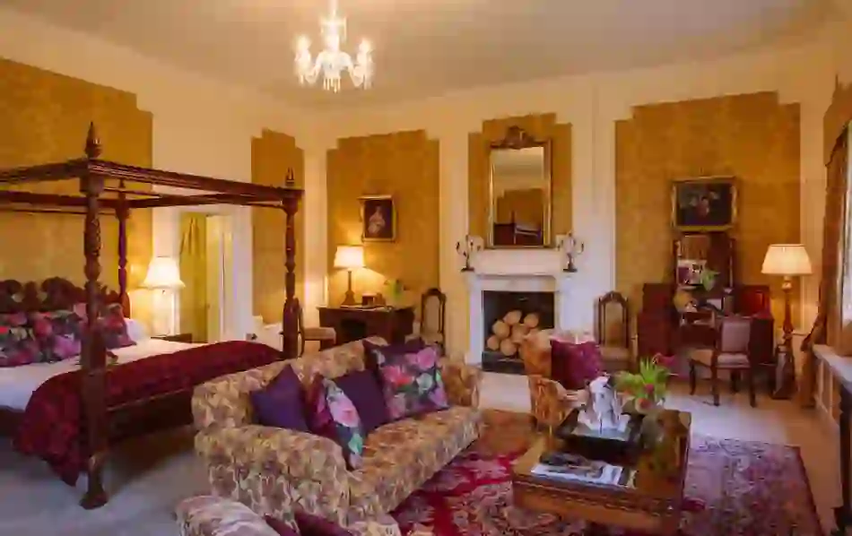Four-poster bed and antique furnishings in a richly decorated heritage suite with fireplace at Waterford Castle.