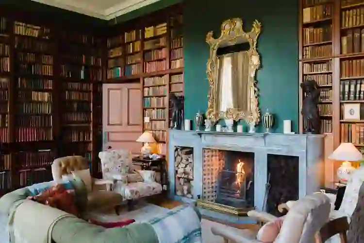 Opulent library lounge with fireplace, gilt mirror, and shelves of antique books at Clonalis House, County Roscommon.