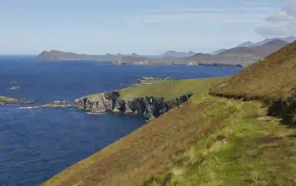 Coastal trail along Great Blasket Island with a view towards the Kerry peninsula and cliffs meeting the Atlantic Ocean below.
