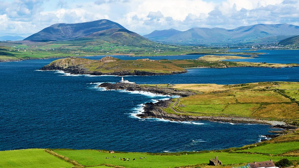 A lighthouse sits on a rocky headland on Valentia Island, framed by blue Atlantic waters and Kerry’s rolling green hills.