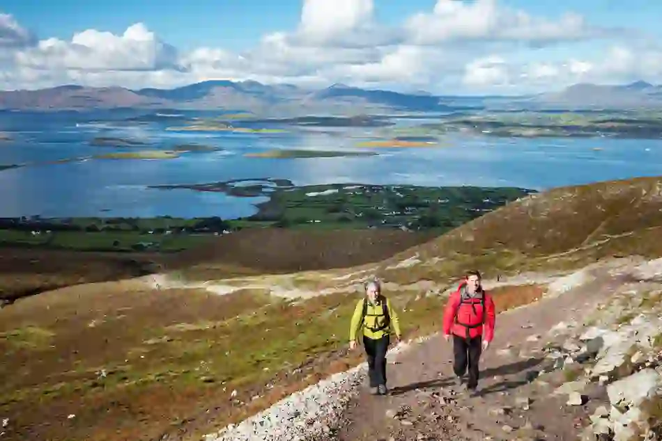 A couple hike a trail on Croagh Patrick in Mayo, with Clew Bay and its many islands stretching out behind them.