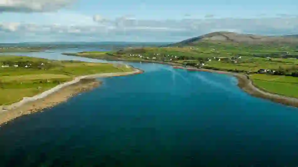 A peaceful inlet at Flaggy Shore, Clare, with blue water winding through green fields and scattered houses.