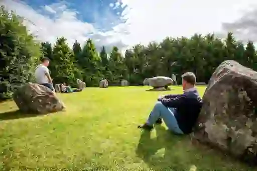 Visitors relaxing beside boulders in the peaceful green setting of the stone circle in Kenmare, Kerry.