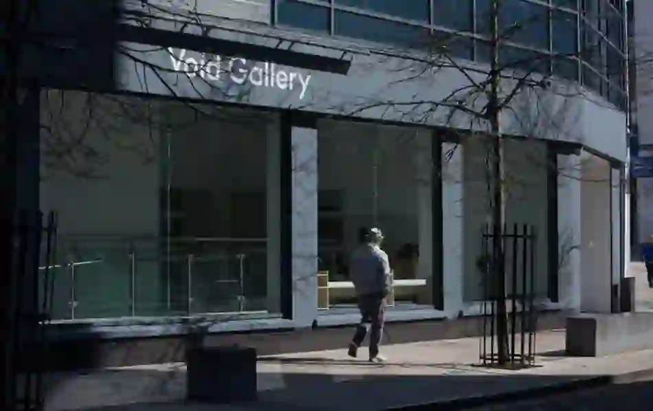 Modern glass-fronted Void Gallery with passerby outside on a quiet street in central Derry~Londonderry.
