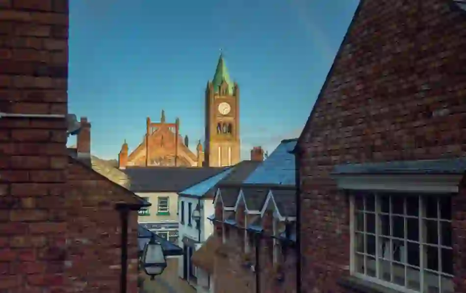 Guildhall clock tower seen above rooftops in Derry’s Craft Village with a morning sky overhead.