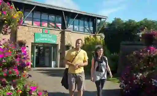 Couple walks past colourful flowers outside Derry’s stone-clad Visitor Information Centre.
