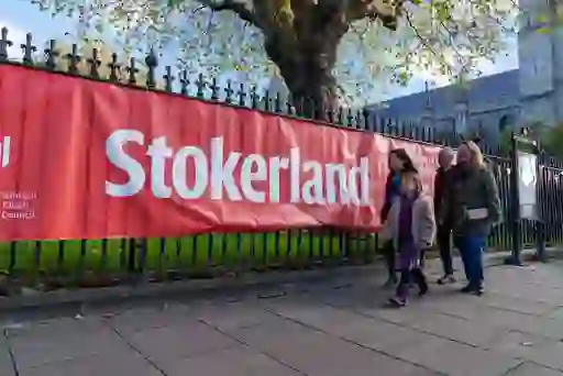 Family walking past a red Stokerland festival banner in Dublin city.