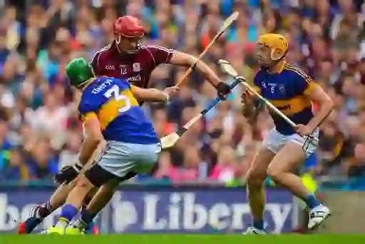Hurling players in helmets competing in a fast-paced match at Croke Park.