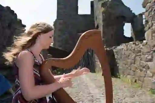 Woman playing a harp among the ruins of Dunluce Castle in County Antrim.