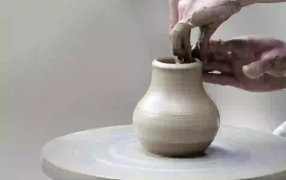 Hands shaping a clay pot on a pottery wheel in an Irish craft workshop.