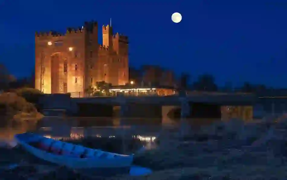 Bunratty Castle illuminated at night beside the River Shannon in County Clare, Ireland.