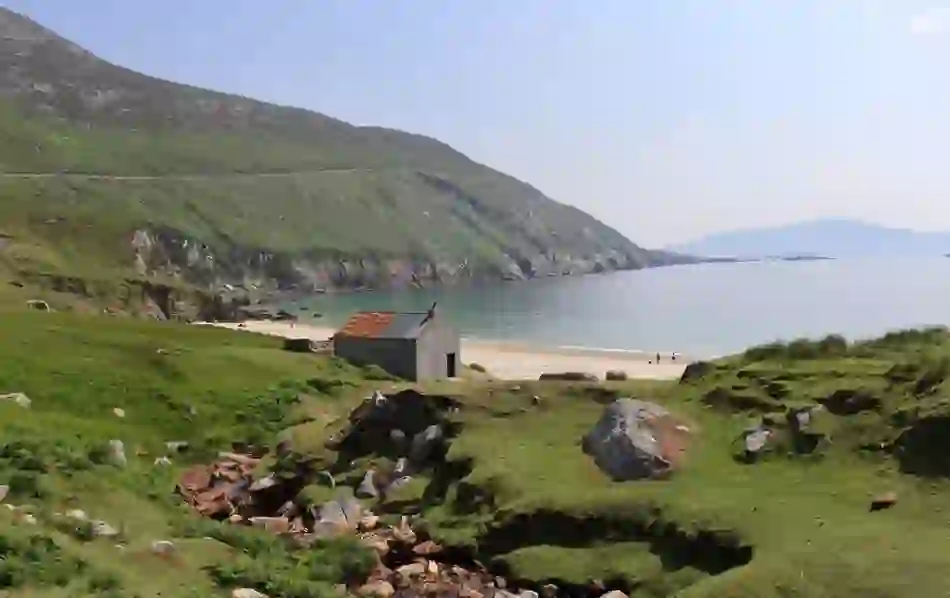Cottage by Keem Bay beach on Achill Island, County Mayo, surrounded by green hills and cliffs.