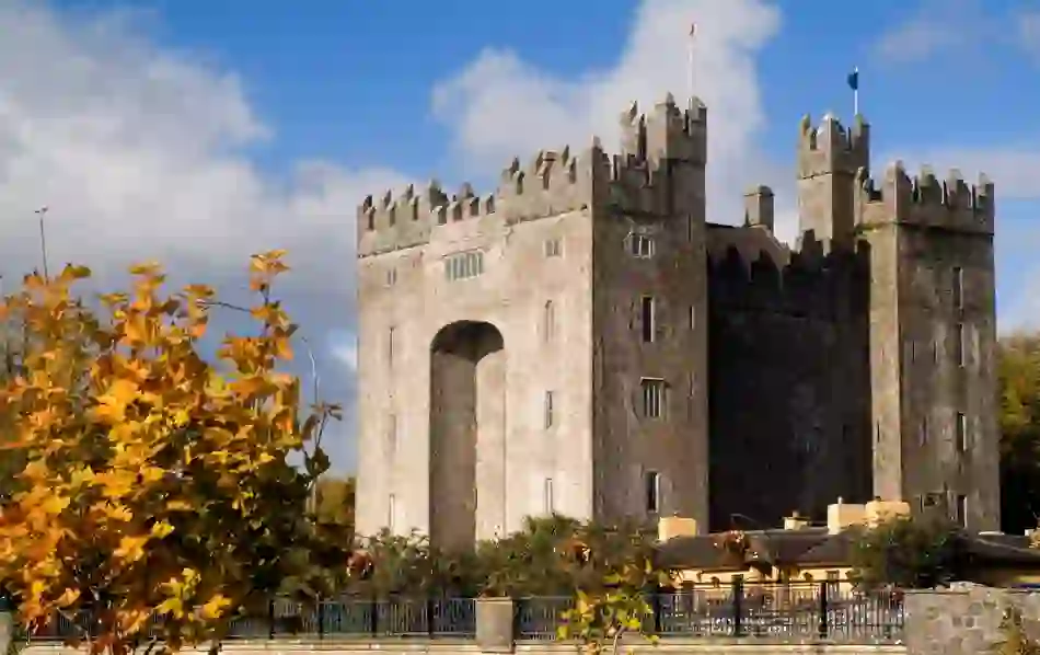 Bunratty Castle in County Clare, Ireland, with golden autumn leaves in the foreground.