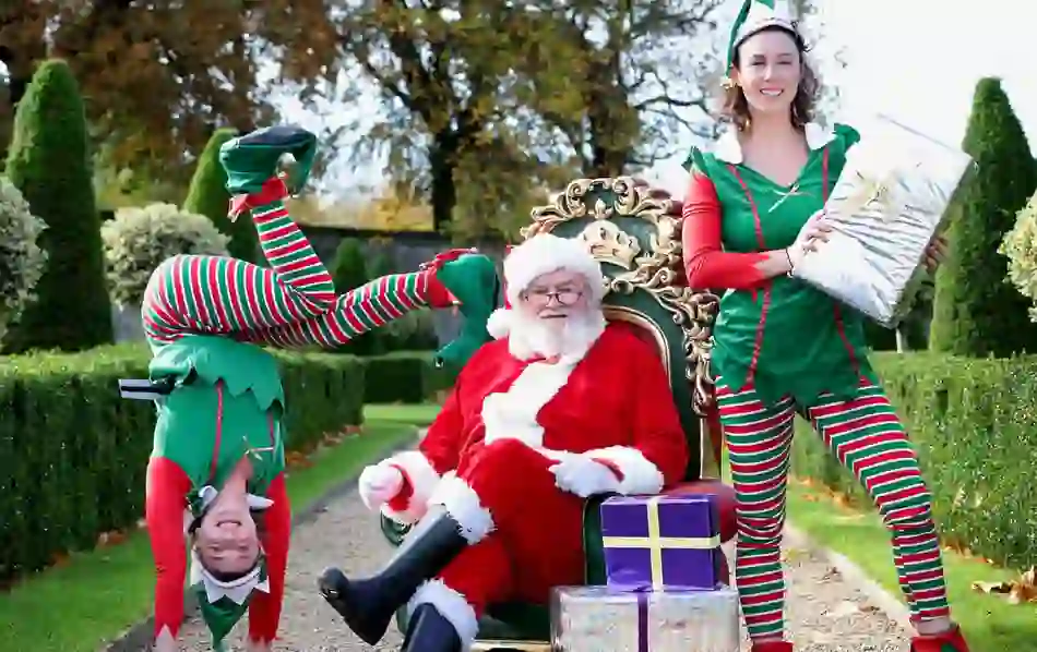 Santa Claus with playful elves posing outdoors with gifts in Ireland.