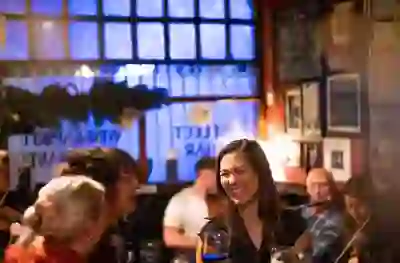 People enjoying music and laughter surrounded by Christmas greenery and warm festive lighting in Smithfield, which hosts the Twinkletown Christmas experience.