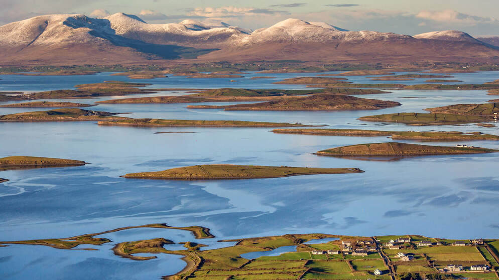 Clew Bay’s small islands with snow-dusted mountains in County Mayo, Ireland, on a clear winter day.