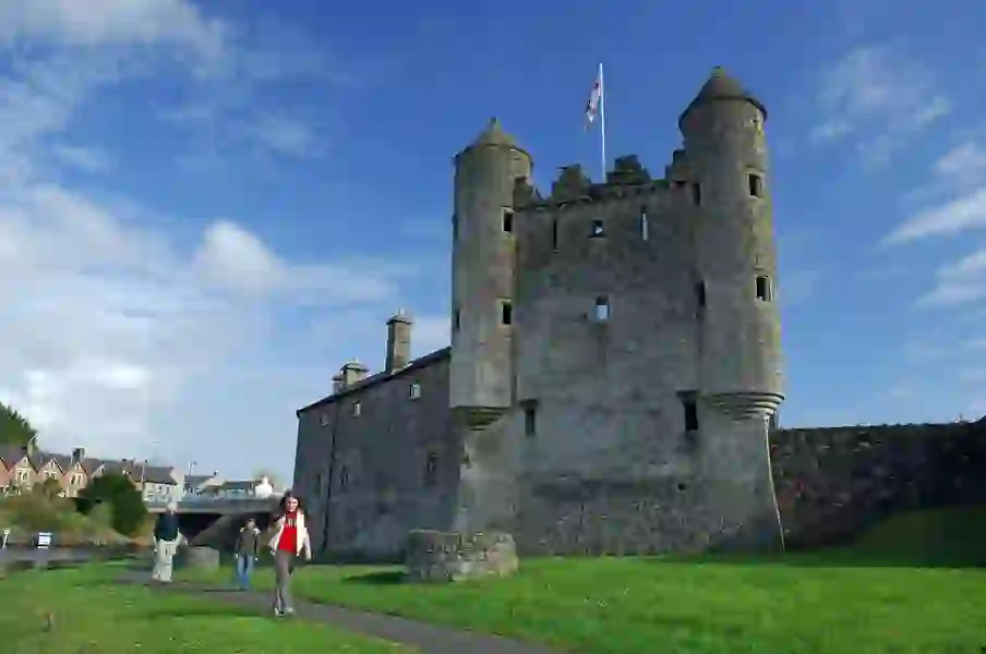 Enniskillen Castle in County Fermanagh with visitors walking outside under blue skies.