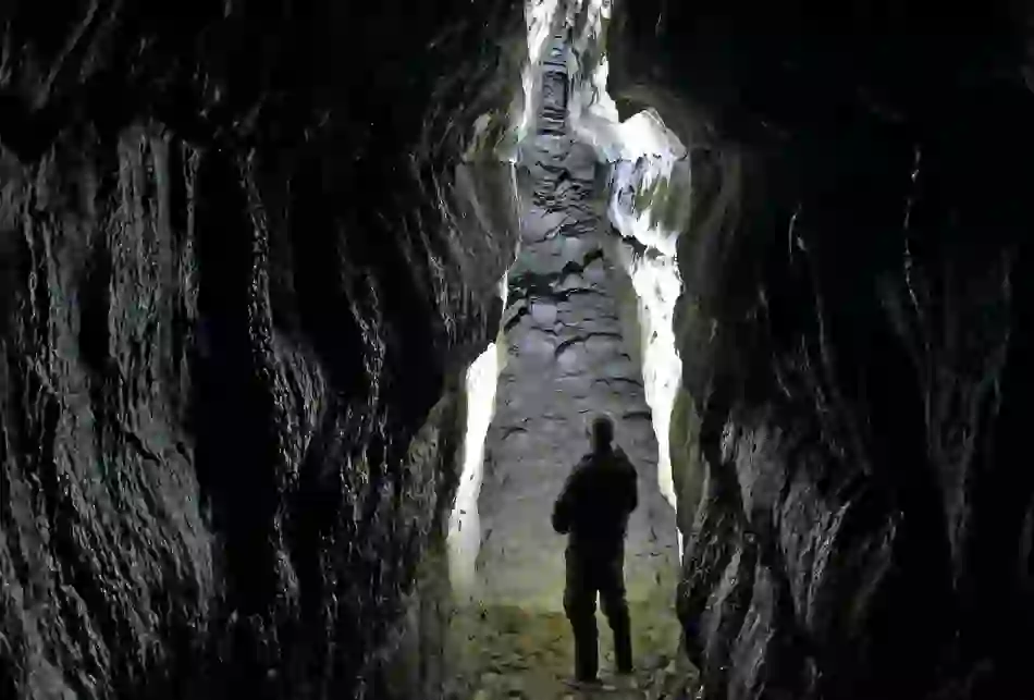 Person standing inside the dark limestone passages of Oweynagat Cave in County Roscommon.