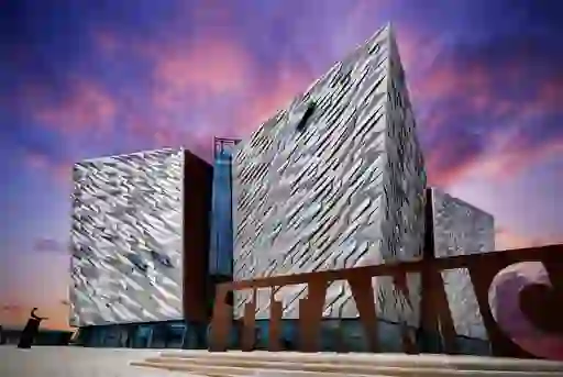 Striking modern façade of Titanic Belfast museum under a vivid purple and pink evening sky.