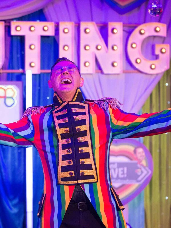 Performer in a rainbow jacket on stage at The Outing LGBTQ+ festival in Ireland.