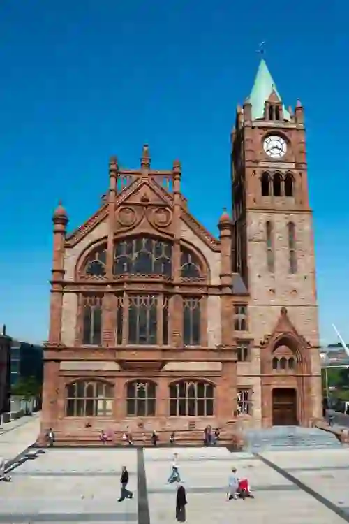 The red-brick Guildhall in Derry~Londonderry with its clock tower against a blue sky.