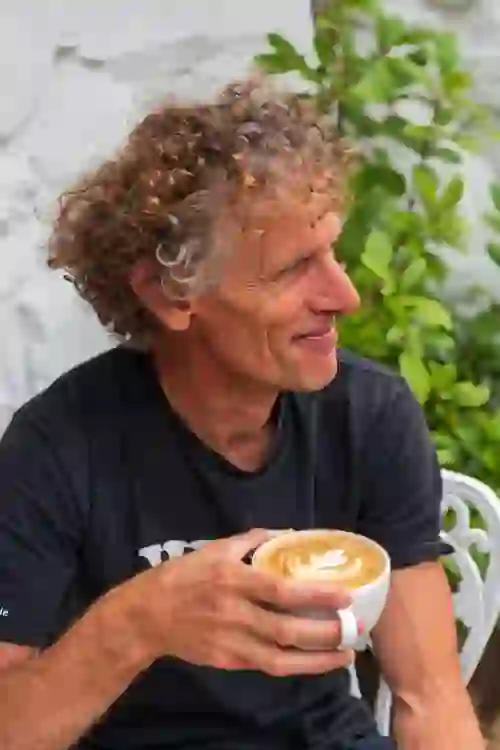 Man smiling while holding a cup of coffee at a café in Derry~Londonderry.