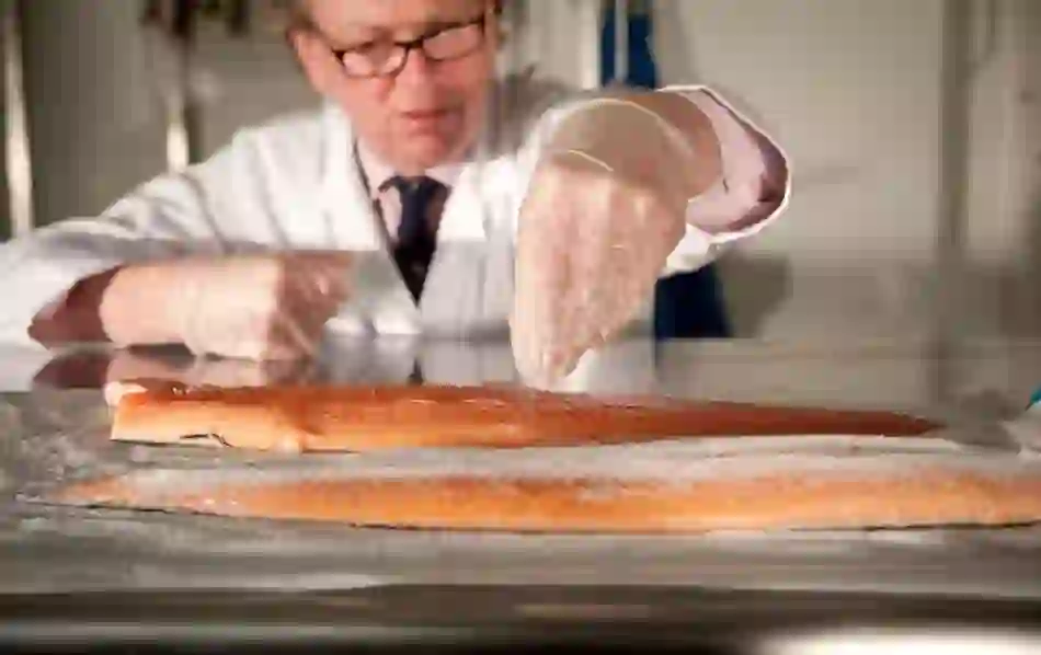 Fishmonger salting fresh salmon fillets at Belvelly Smokehouse.