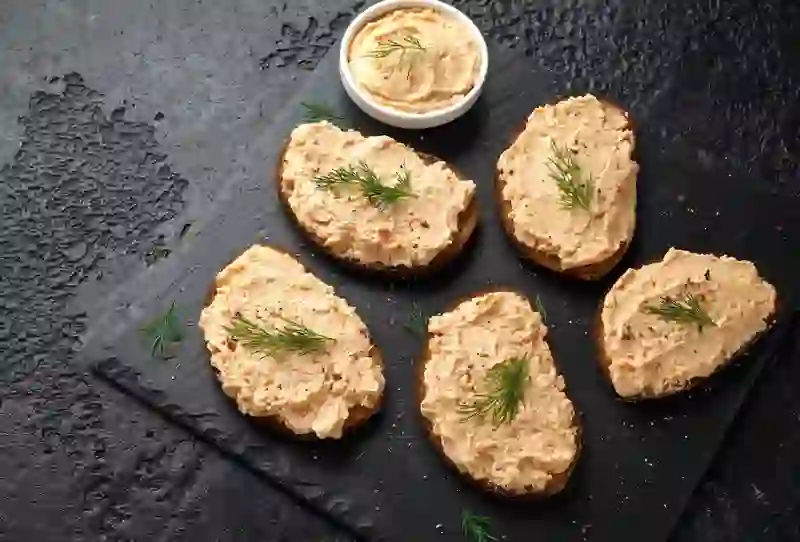 Smoked salmon pâté on brown bread crostini, garnished with fresh dill.