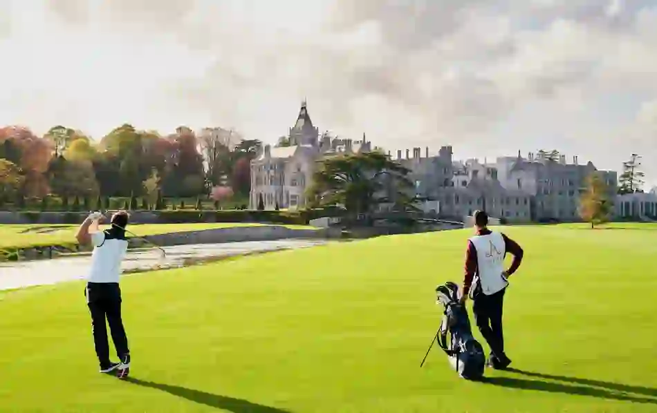 Golfer teeing off with a caddie beside him at Adare Manor’s championship course in County Limerick.