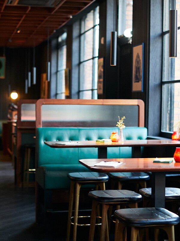 Stylish restaurant interior in Smithfield, Dublin, with green leather booths, large windows, and warm lighting.