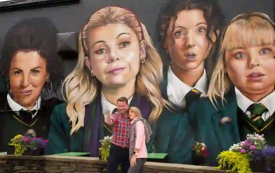 Tourists take a selfie in front of the vibrant Derry Girls mural in Derry~Londonderry, Northern Ireland.