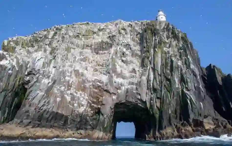Bull Rock’s dramatic sea arch and lighthouse surrounded by seabirds, rising from the ocean off County Cork.