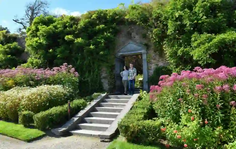 Couple walking through a floral archway in Mount Congreve’s walled garden.