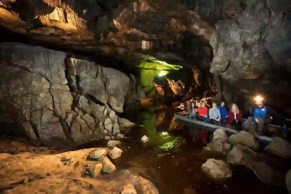 Tourists on a guided boat ride through Marble Arch Caves, with dramatic rock formations and underground water.