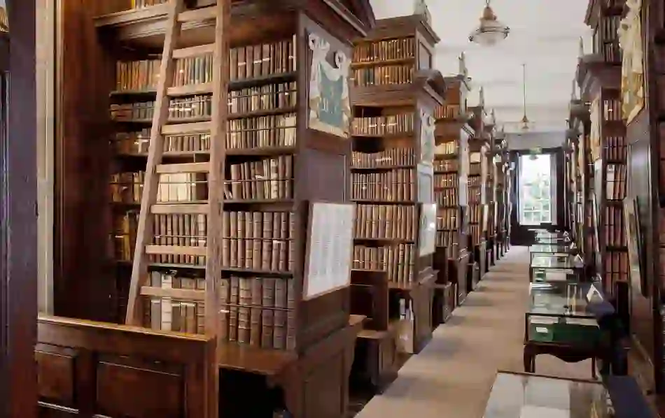Interior of Marsh’s Library in Dublin with rows of antique books, wooden reading alcoves, and tall sliding ladders.