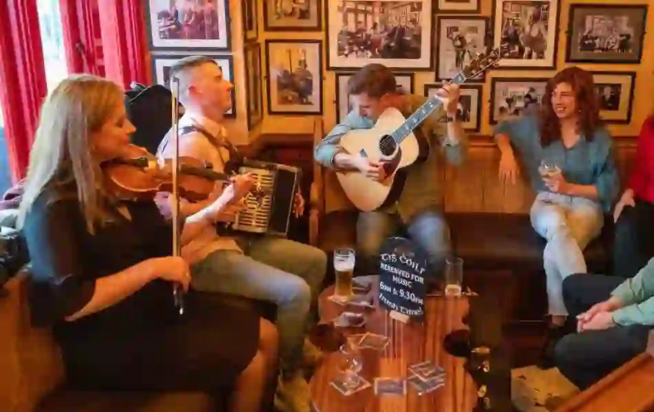 Trad musicians play fiddle, accordion and guitar at Tigh Cóilí pub, Galway, as patrons enjoy the session.