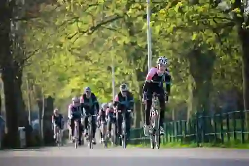 Competitive cyclists in matching kit ride through a tree-lined road in Armagh during a springtime cycling event.