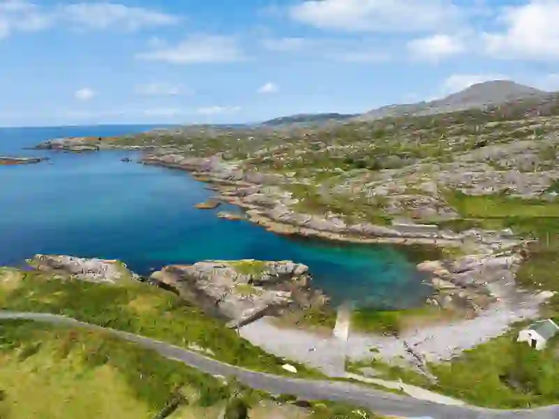 Winding coastal road above turquoise coves and rocky shoreline on the Ring of Beara, Cork.