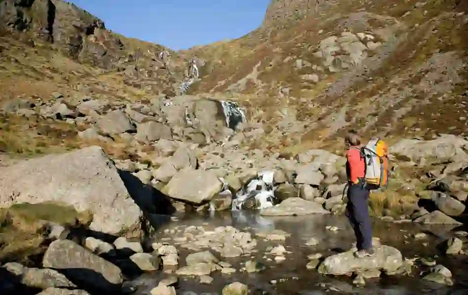 Walker pausing beside boulders near Mahon Falls in the Comeragh Mountains, County Waterford.