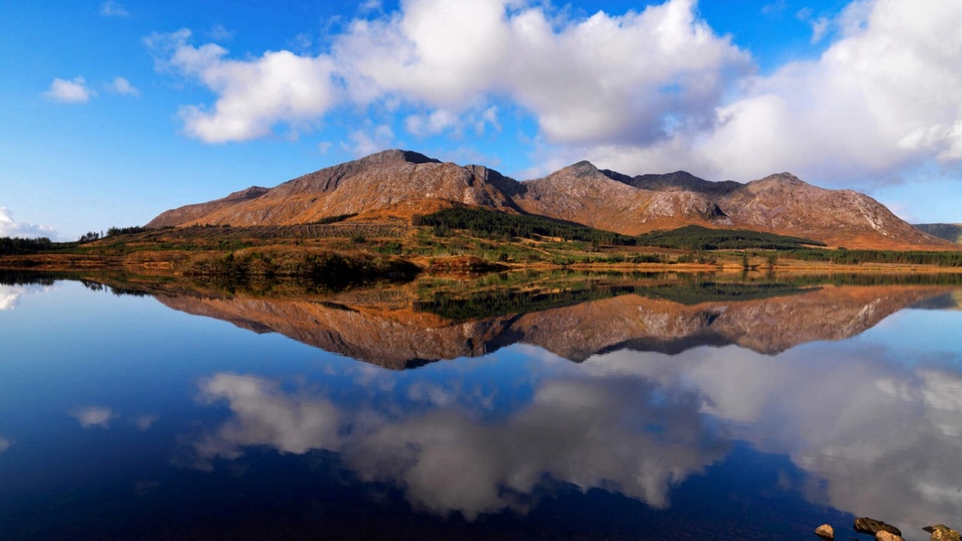 Cloud-covered Twelve Bens mountains mirrored in the calm waters of Lough Inagh in Connemara.
