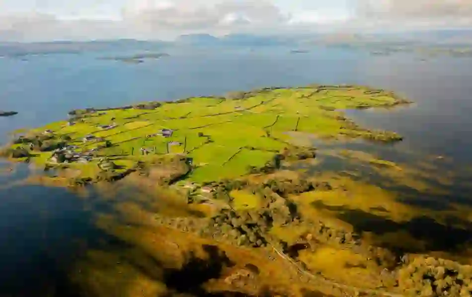 Aerial view of green patchwork fields and scattered cottages beside Lough Corrib in County Galway.
