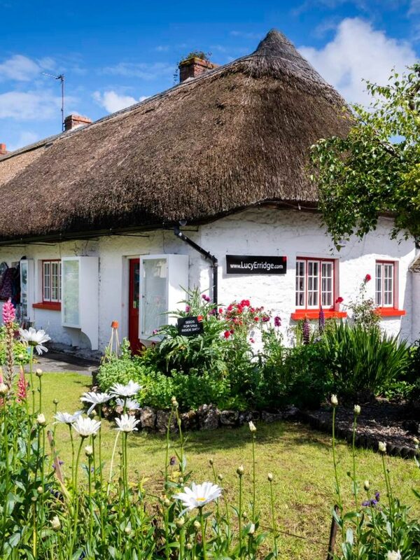Thatched cottage with whitewashed walls and sign for Lucy Erridge in Adare village, County Limerick.
