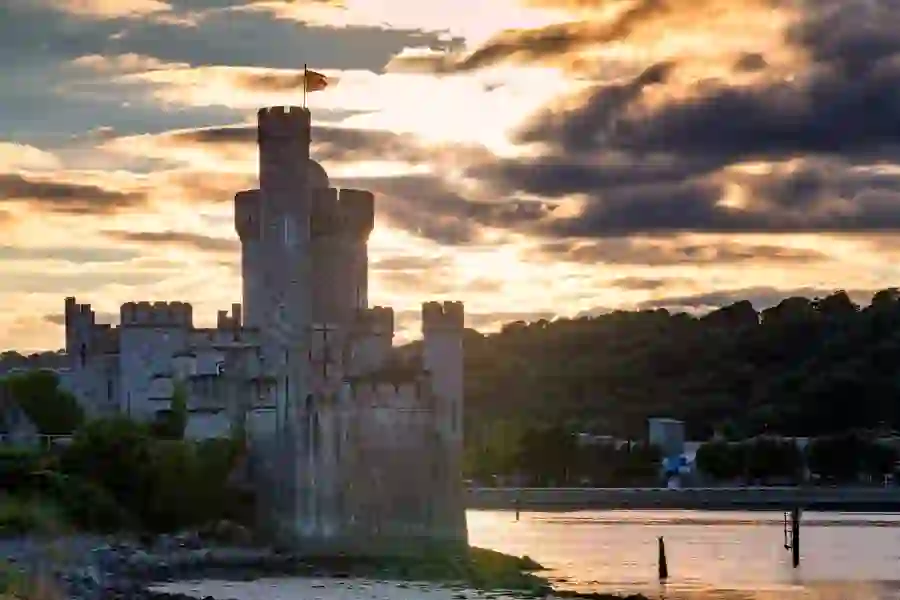 Sunset view of Blackrock Castle on the River Lee, with golden light reflecting off the water and dramatic clouds overhead.