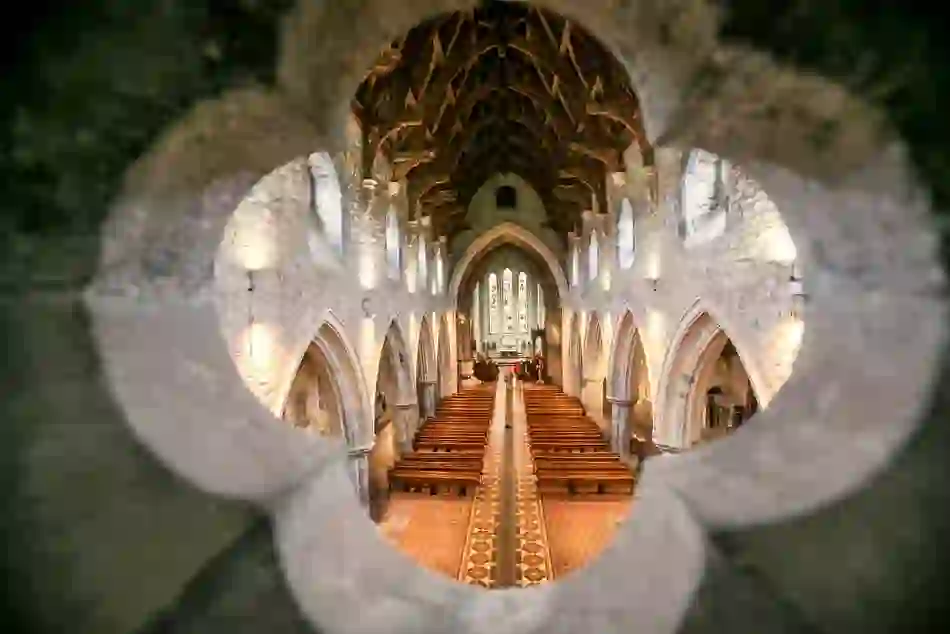 Interior of St Canice’s Cathedral viewed through a quatrefoil stone window, with ornate wooden roof.