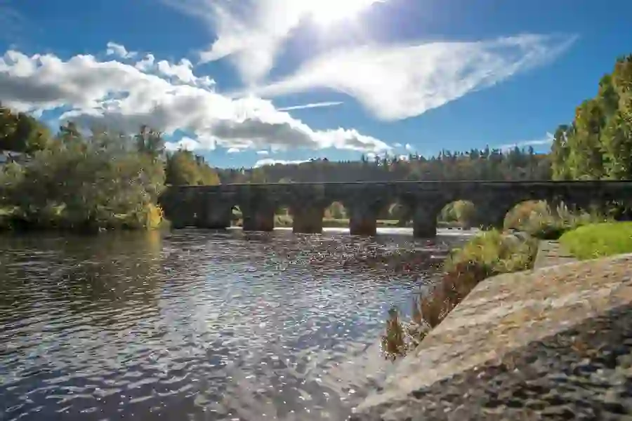 Historic stone arch bridge spanning a calm river under a bright sky in Inistioge, County Kilkenny.