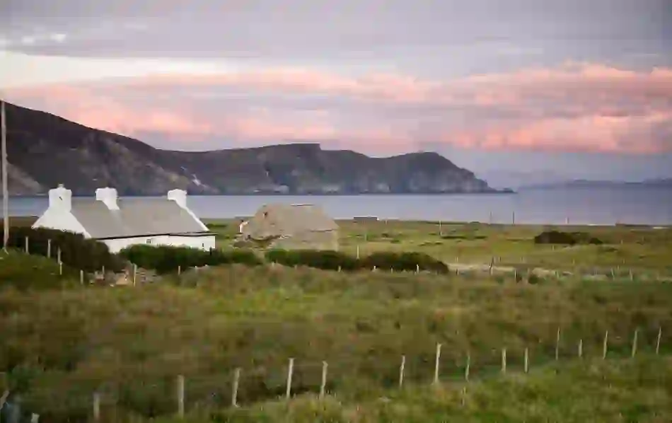 Traditional cottages and stone ruins overlook grassy fields and cliffs above the Atlantic on Achill Island.