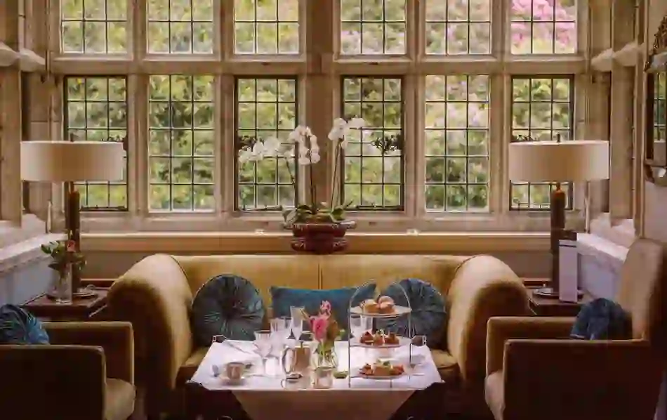 Afternoon tea is set in a plush lounge at Waterford Castle, framed by elegant leaded windows.
