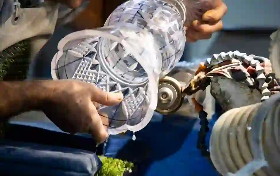 A craftsman cuts intricate patterns into a glass vase at the House of Waterford Crystal.
