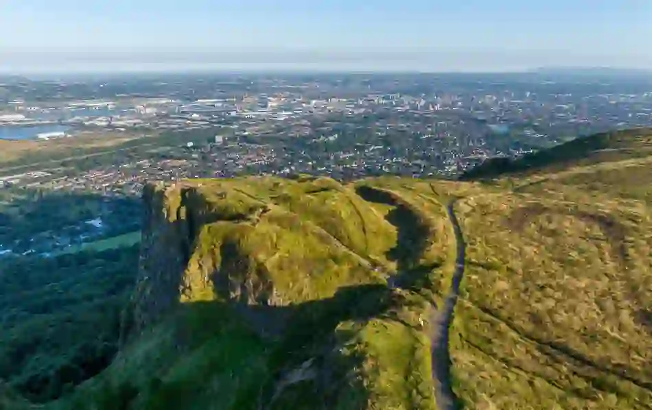 Morning mist rolling over the cliffs and wooded slopes of Cave Hill near Belfast in County Antrim.